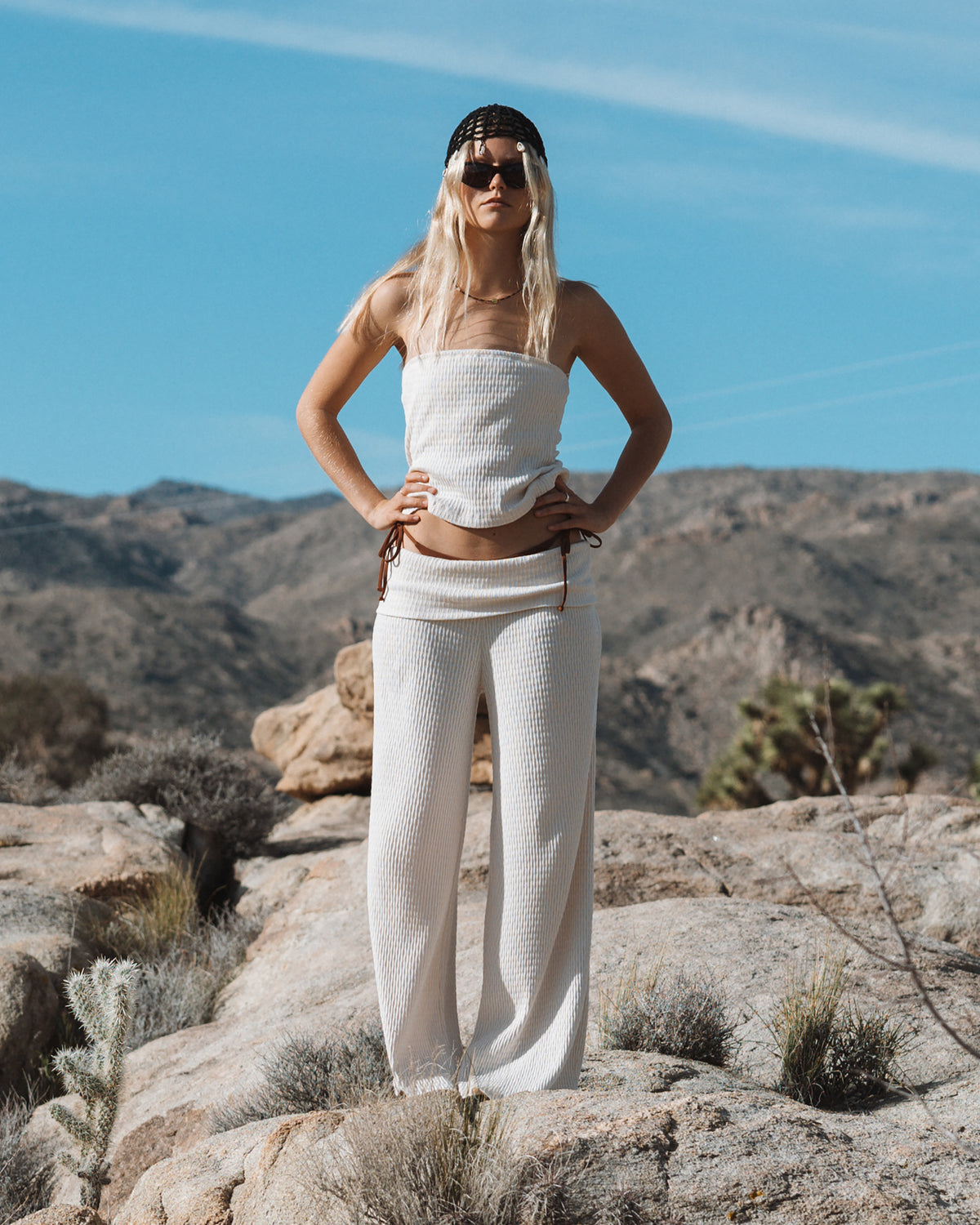 White ribbed tube top and matching pants worn with sunglasses and white cap.