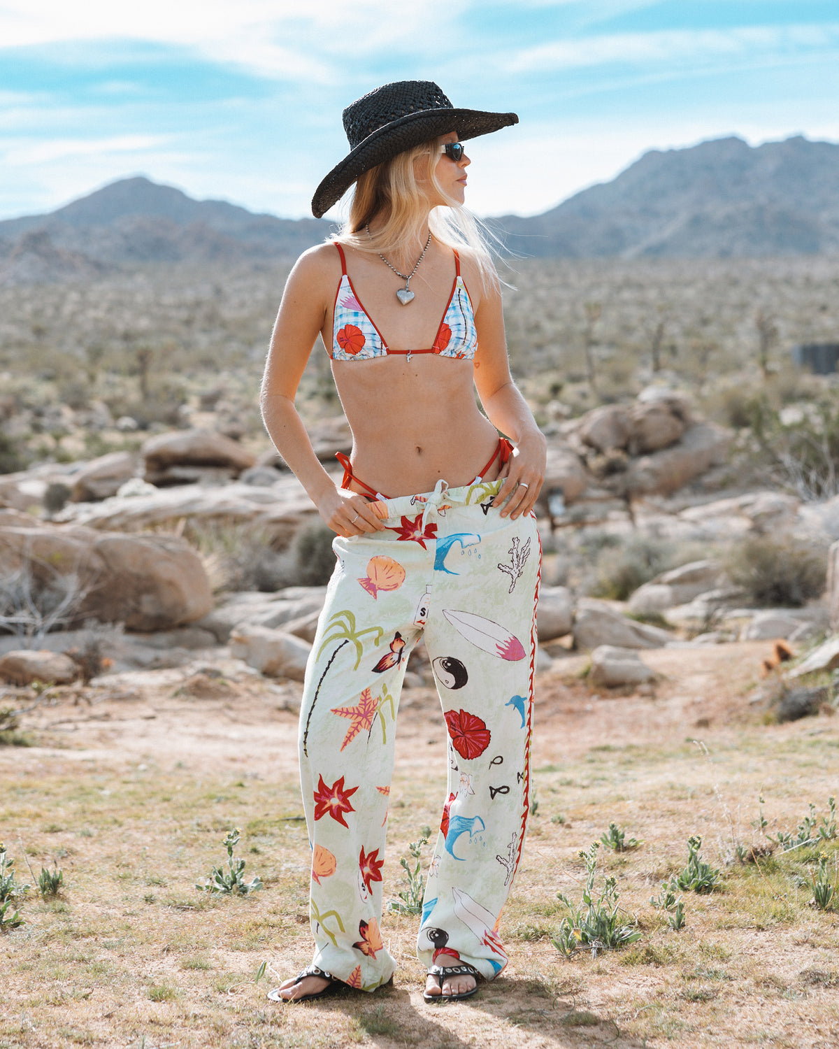 Cream pants with colorful floral and botanical print, elastic waist, worn with bikini top in desert setting.
