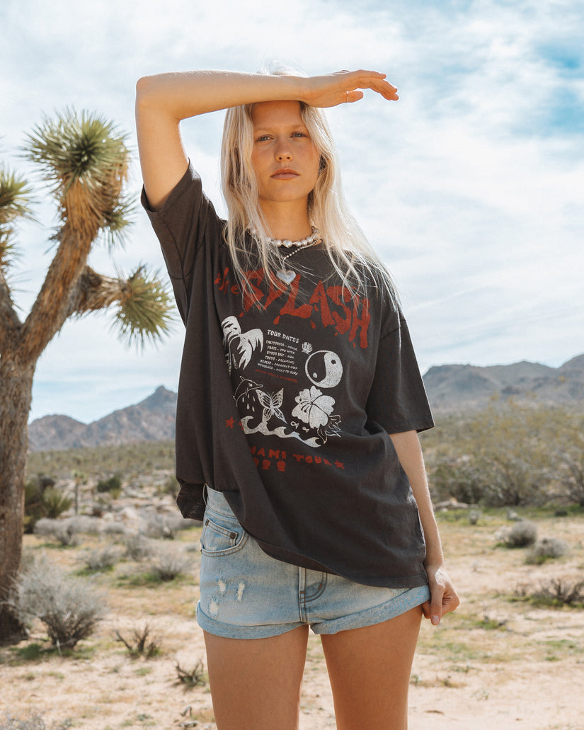 Off-black short sleeve t-shirt with red and white graphic print on front, worn with light blue denim shorts.