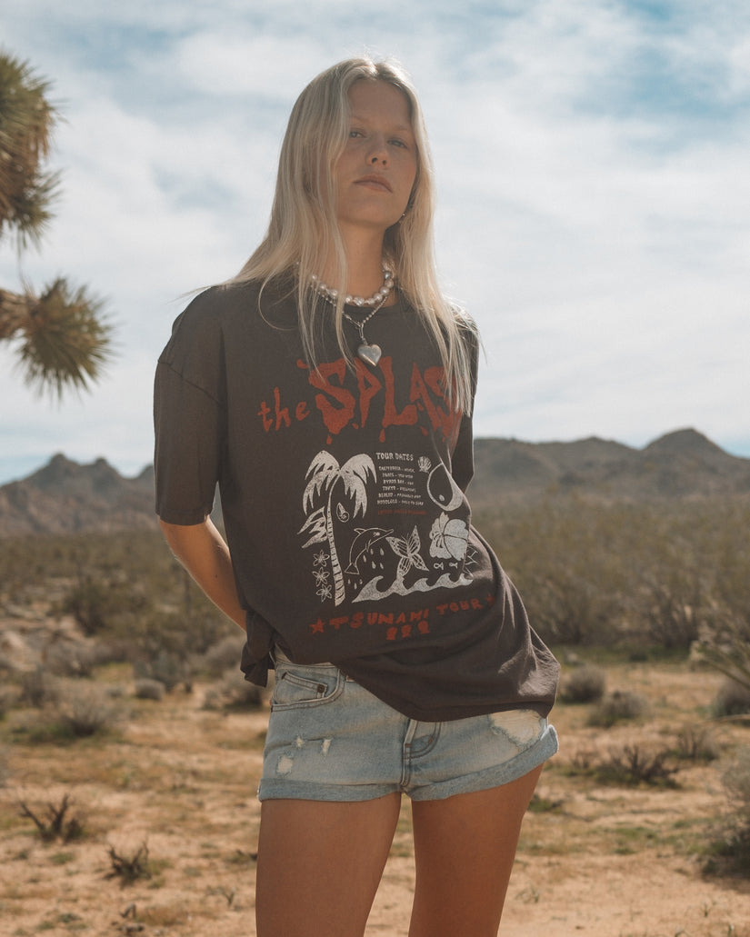 Person wearing off-black short sleeve t-shirt with graphic design and denim shorts in desert landscape.