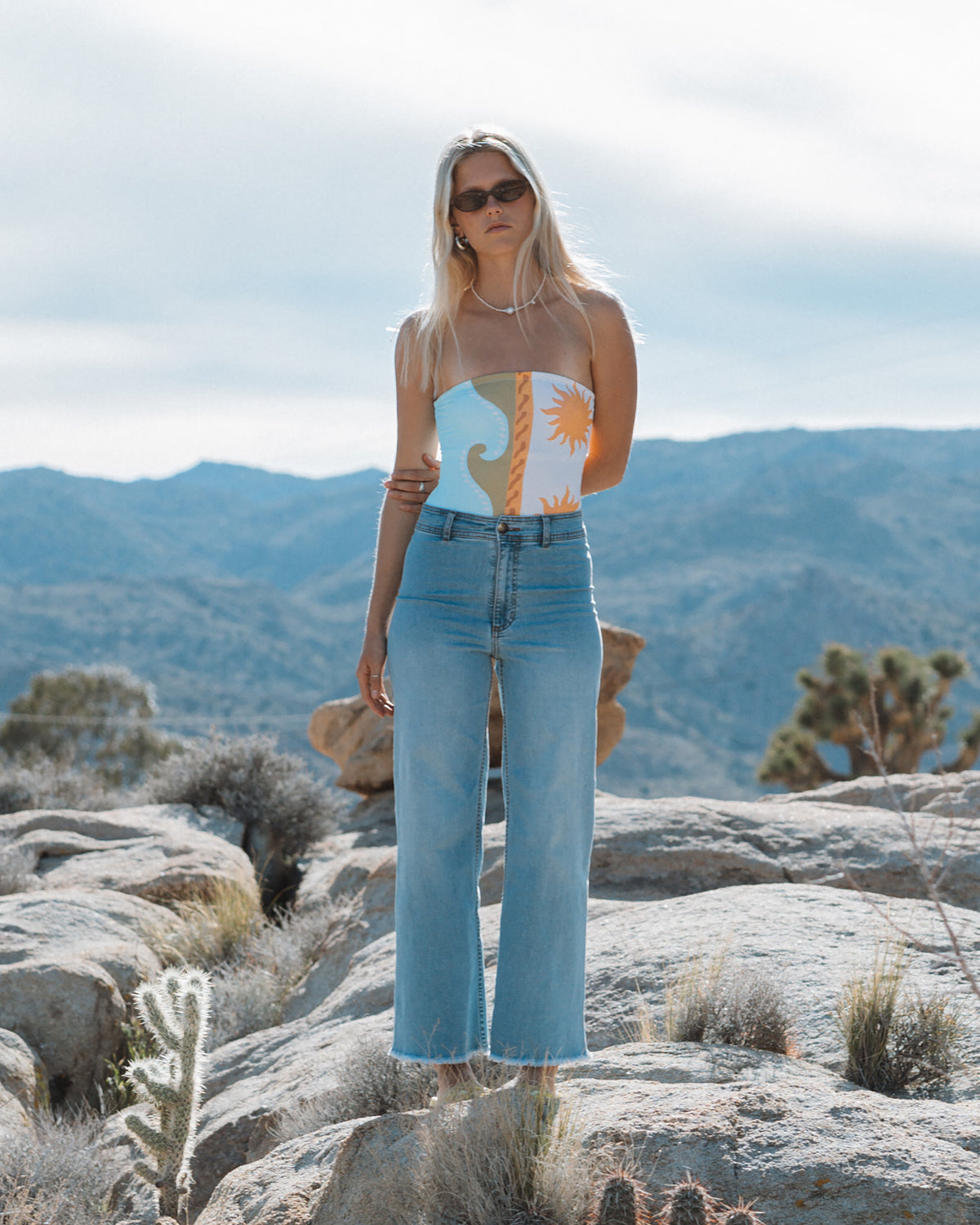 Light blue high-waist denim pants with raw hem, worn with patterned crop top.