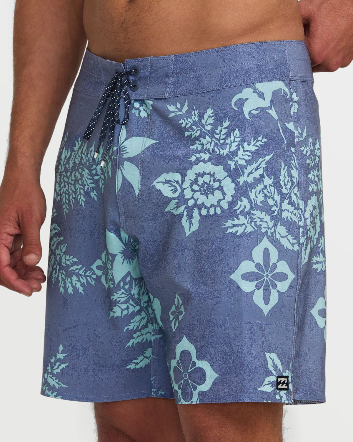 Blue boardshorts with light blue floral and botanical print, drawstring waist, and 18" inseam.