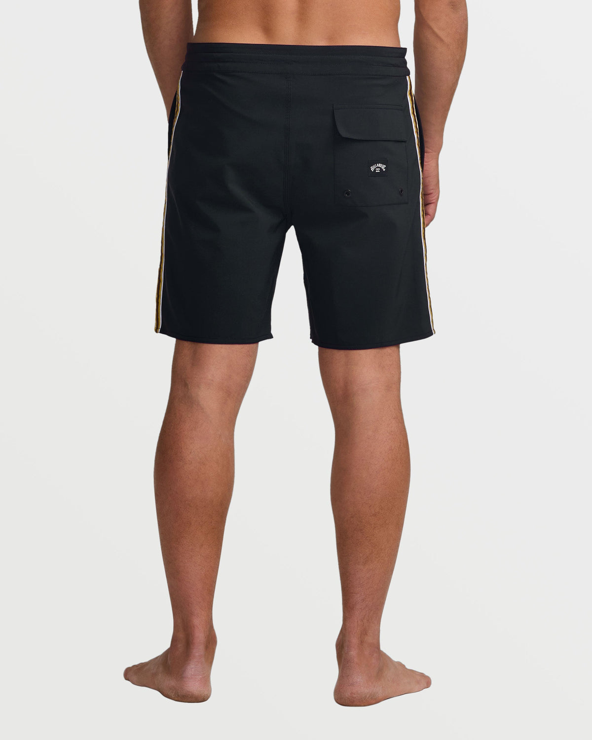 Black boardshorts with gold side stripes and back pocket, worn by male model shown from behind.