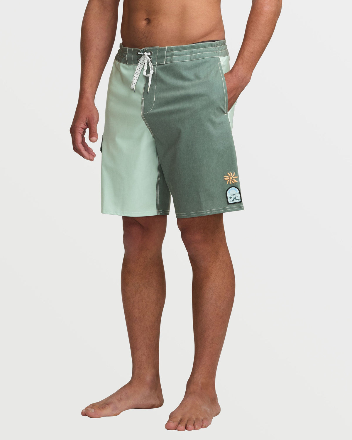 Men's green tea boardshorts with white drawstring, sun and wave logos on leg.