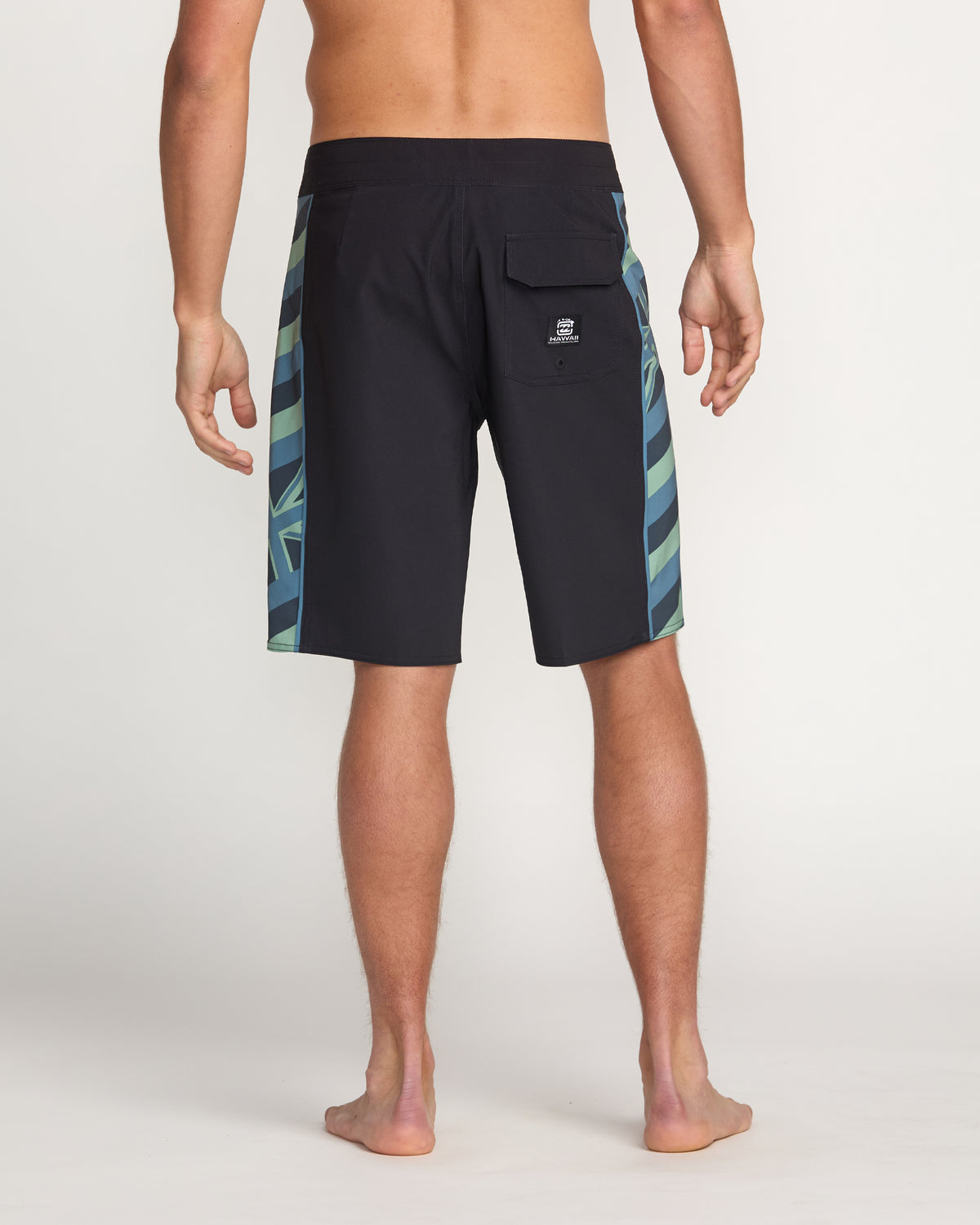 Black boardshorts with teal and green geometric striped side panels, back pocket, and branded logo patch.
