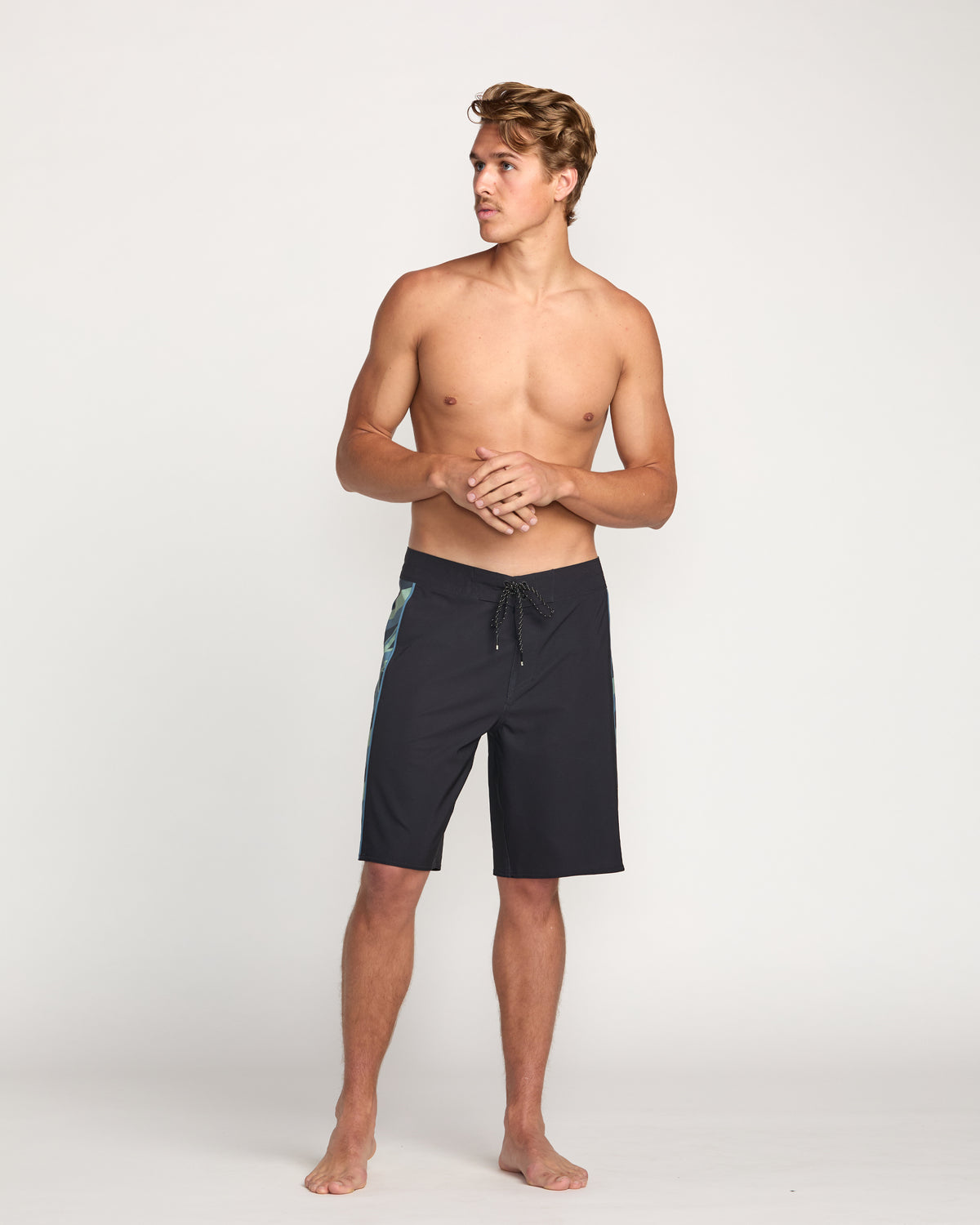 Man wearing black boardshorts with teal side stripe and drawstring waistband, knee-length cut.