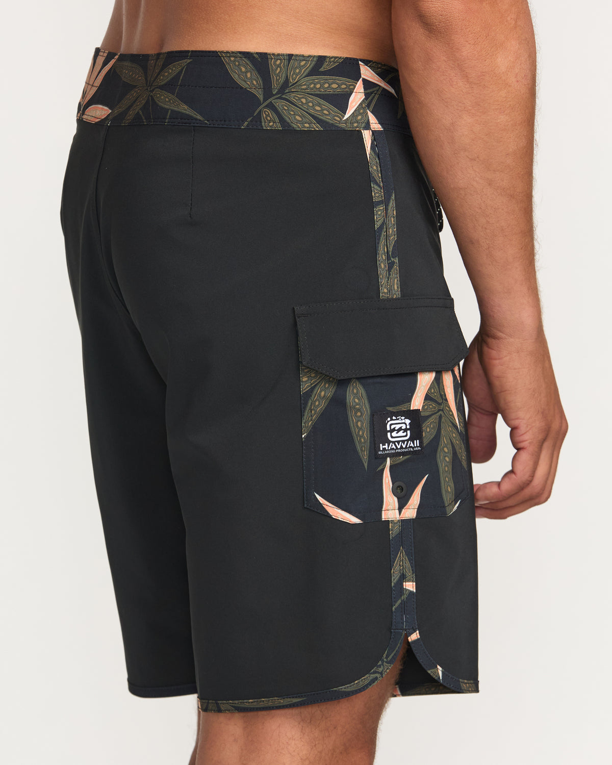 Black 18" boardshorts with geometric patterned waistband and cargo pocket, worn by male model.