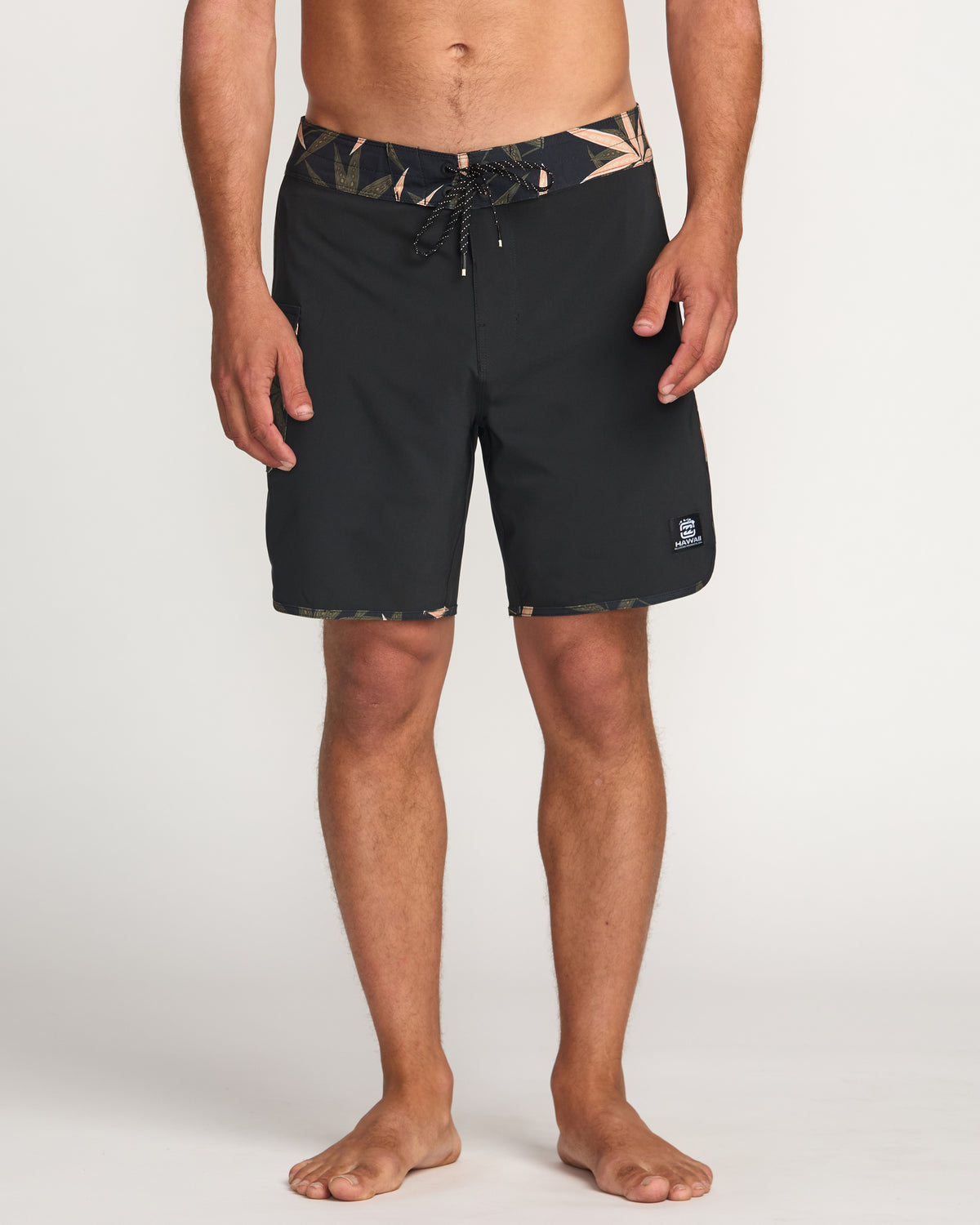 Black 18" boardshorts with geometric patterned waistband and drawstring, worn by male model.