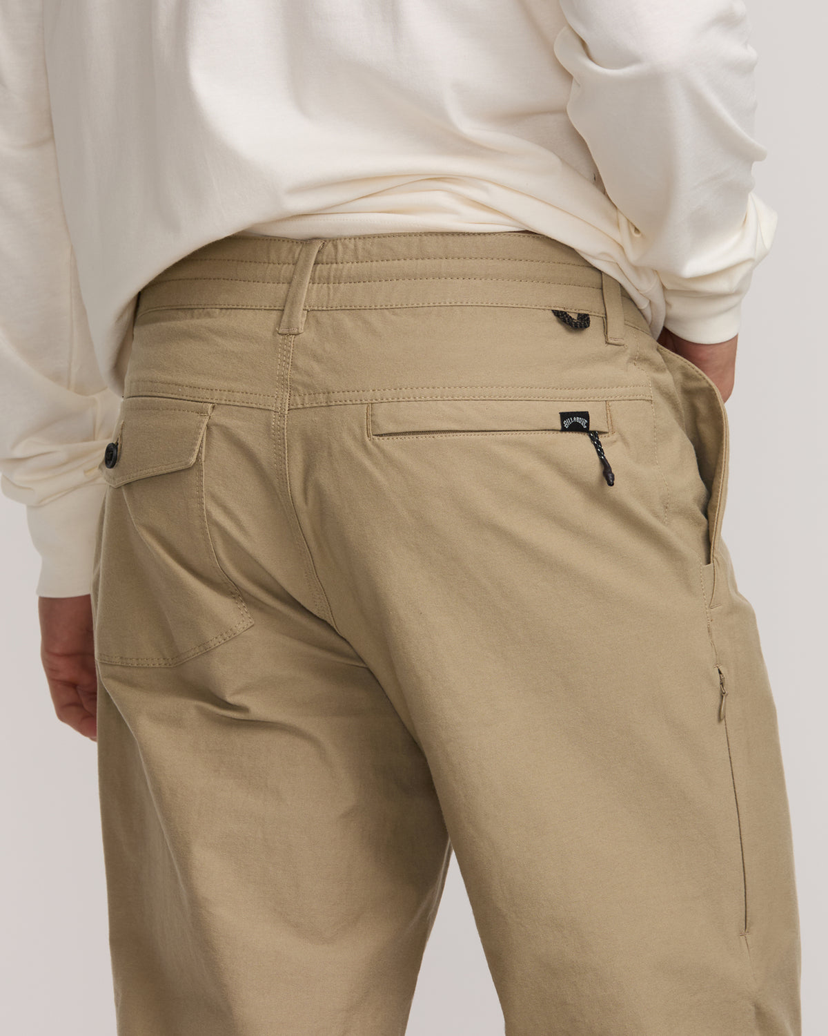Tan Surftrek Plus Pant with multiple pockets, zipper details, and branded patches shown from rear waist down.