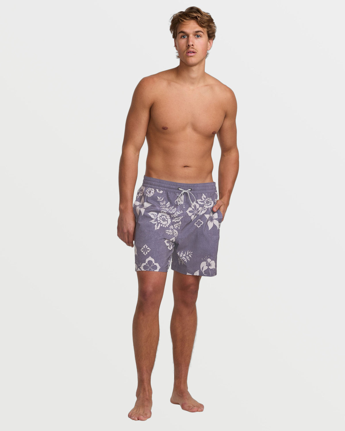Man wearing light purple swim trunks with white floral and geometric patterns, elasticated waistband, and side pockets.