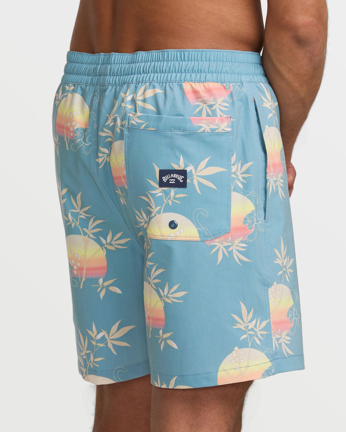 Washed blue swim trunks with tropical sunset and leaf pattern, elastic waistband, and back pocket with brand label.