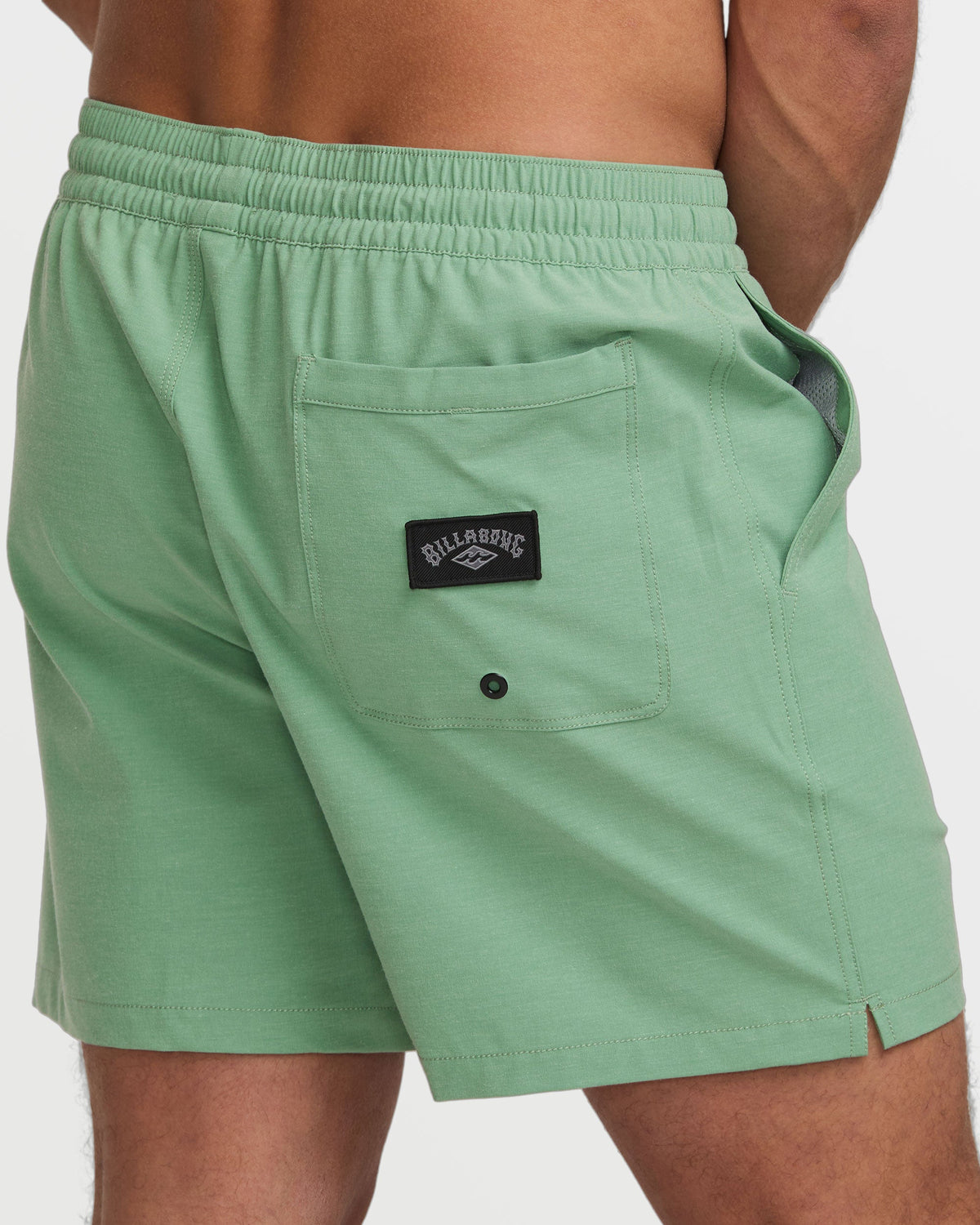 Moss green swim trunks with elastic waistband, front patch pocket, and Billabong brand label.