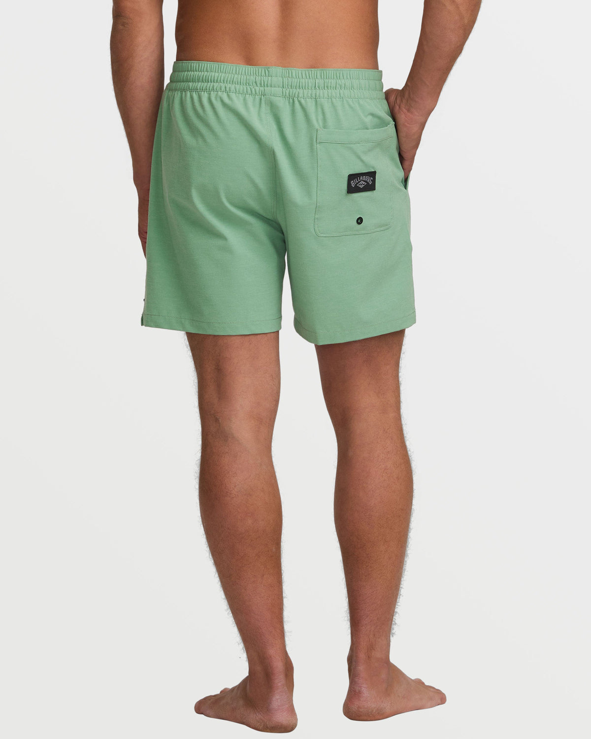 Moss green swim trunks with elastic waistband, back pocket, and button closure on male model.