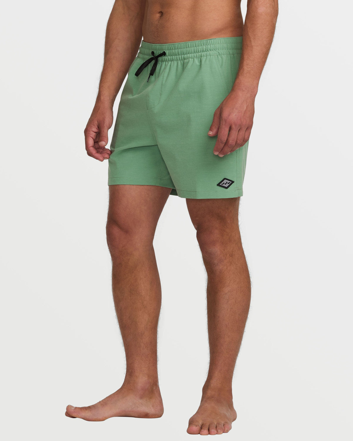 Moss green swim trunks with elastic waistband, drawstring, and small logo patch on thigh.