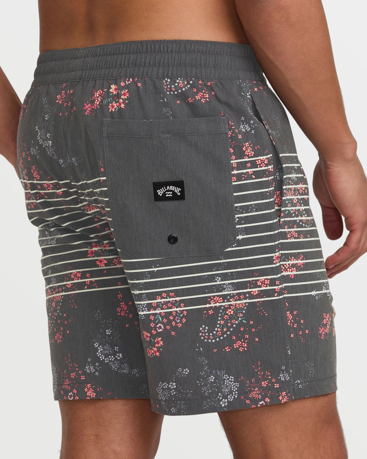 Charcoal swim trunks with red and white floral print, horizontal stripes, front pocket, and Billabong logo.