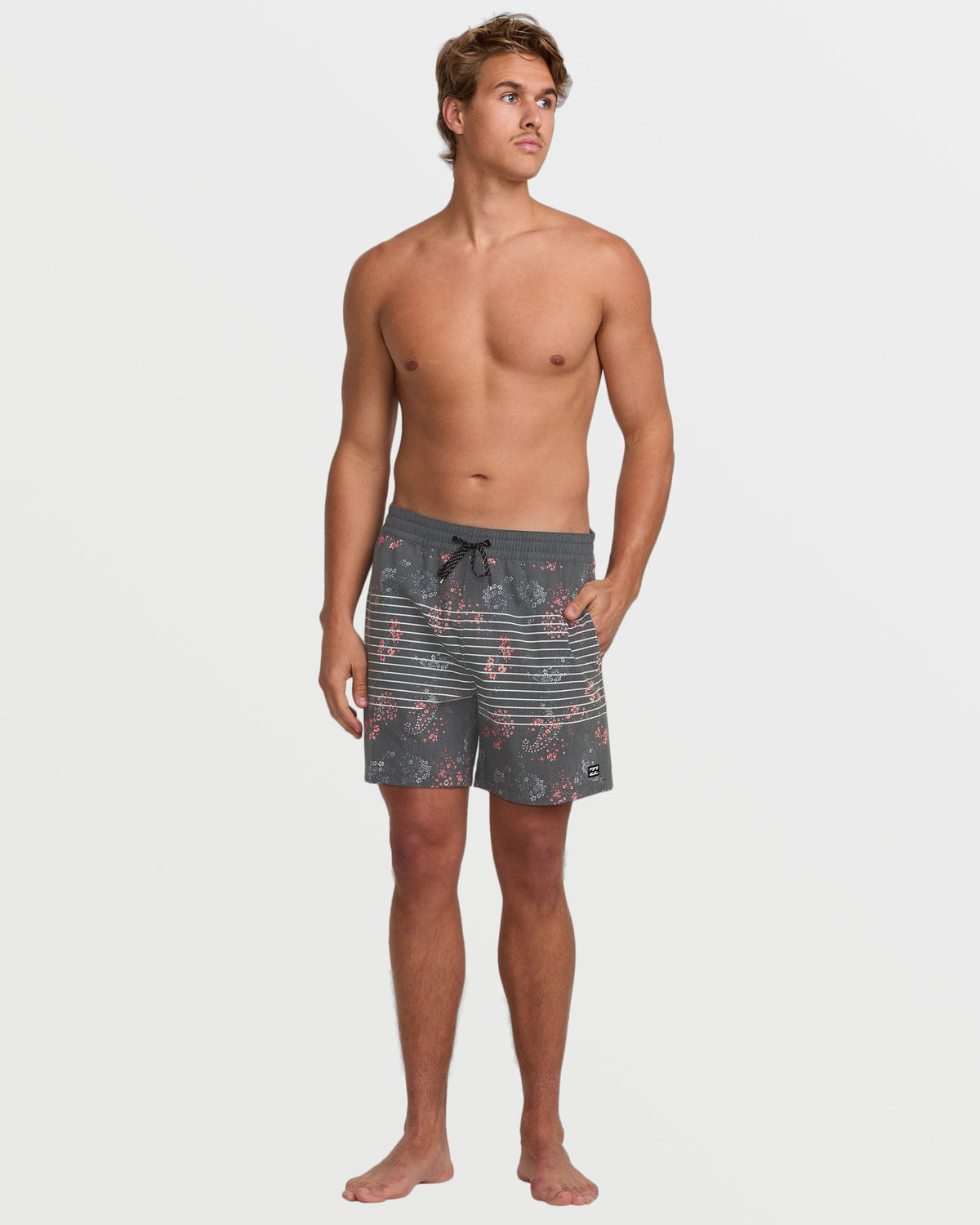 Man wearing gray swim trunks with floral and striped pattern, drawstring waist, knee-length cut.
