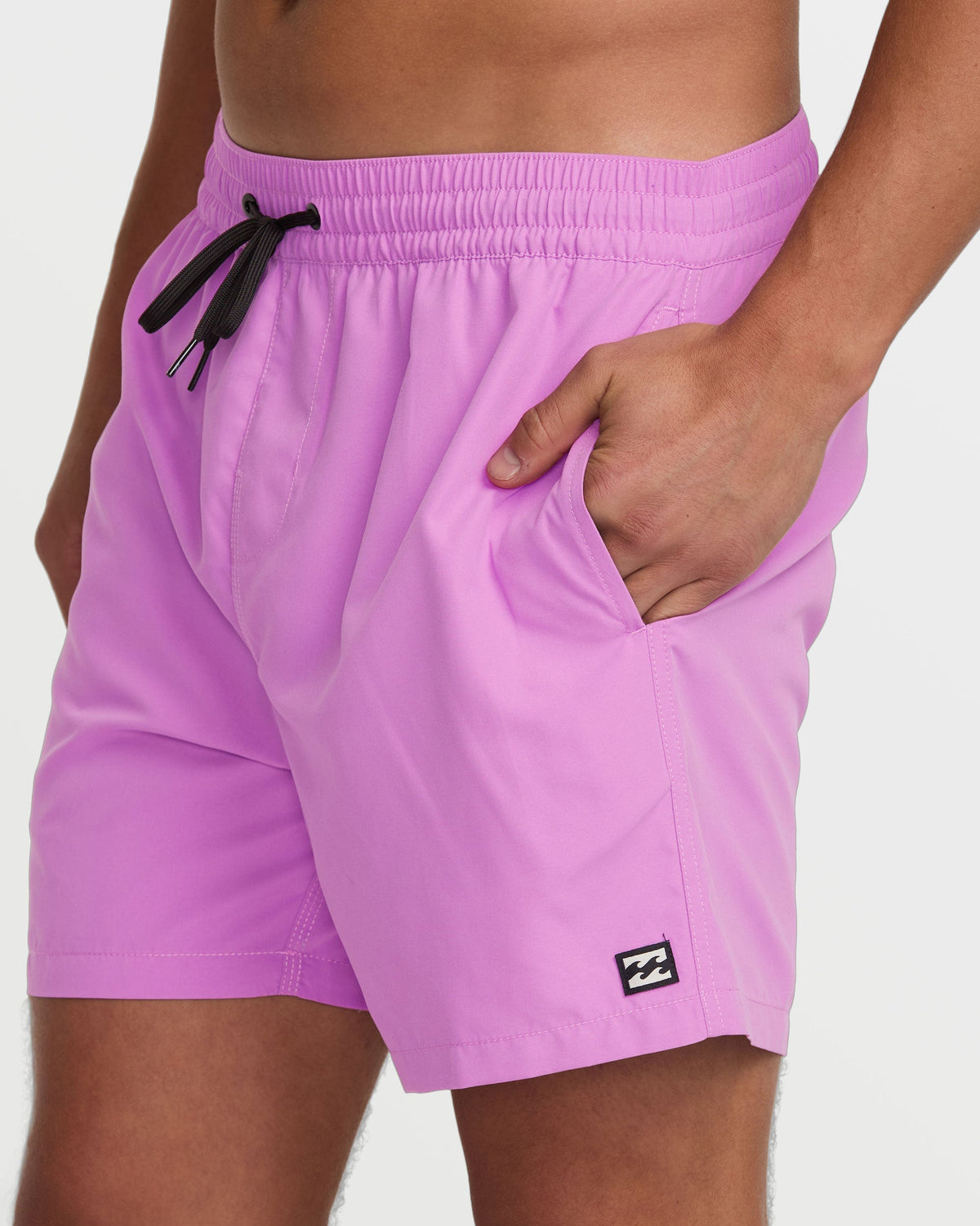 Fuschia swim trunks with black drawstring, side pockets, and brand logo patch on leg.