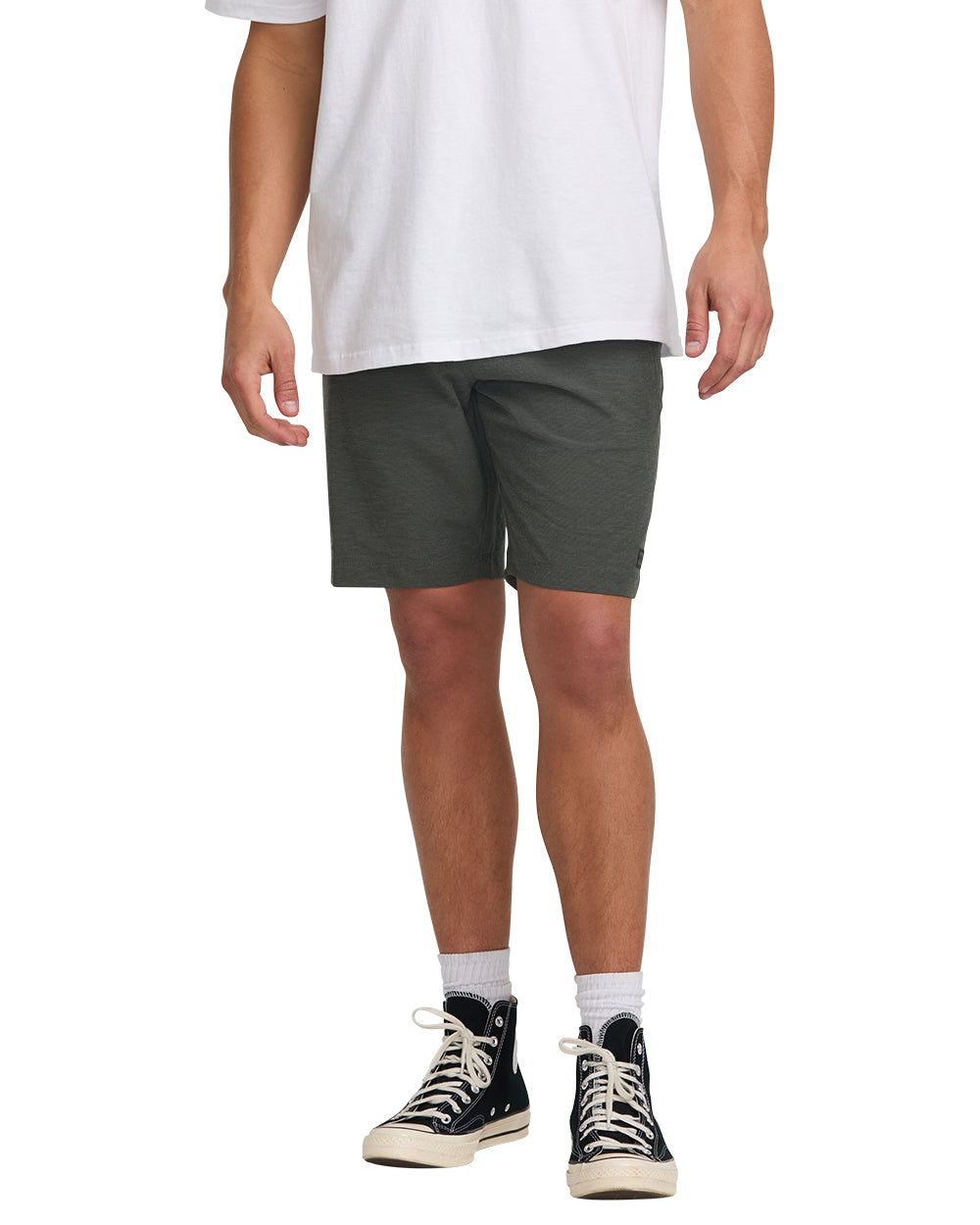 Man wearing white t-shirt and dark gray hybrid shorts with black and cream sneakers.
