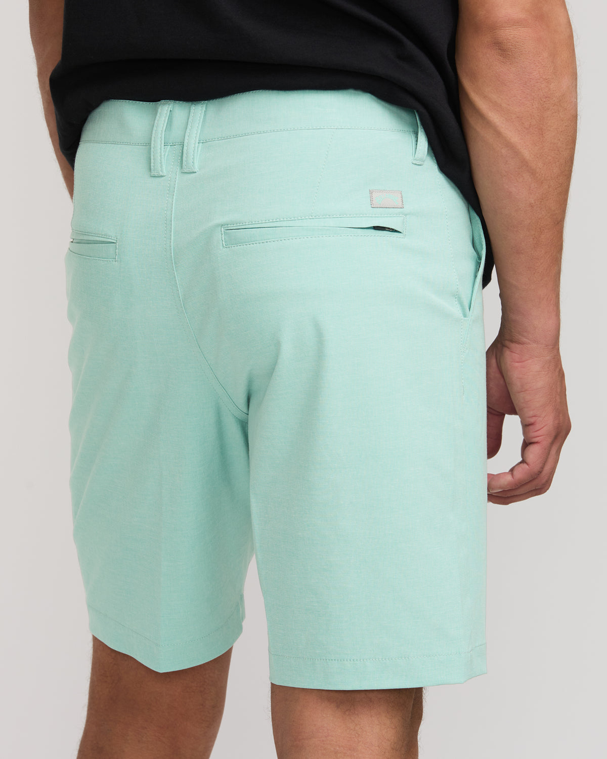 Light mint green hybrid shorts with drawstring waistband, front zip pocket, and back flap pocket on male model wearing black 