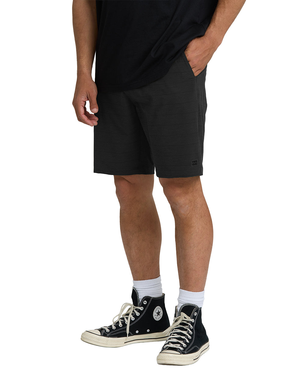 Black hybrid shorts with front pockets and textured fabric, shown on a model wearing a black shirt.