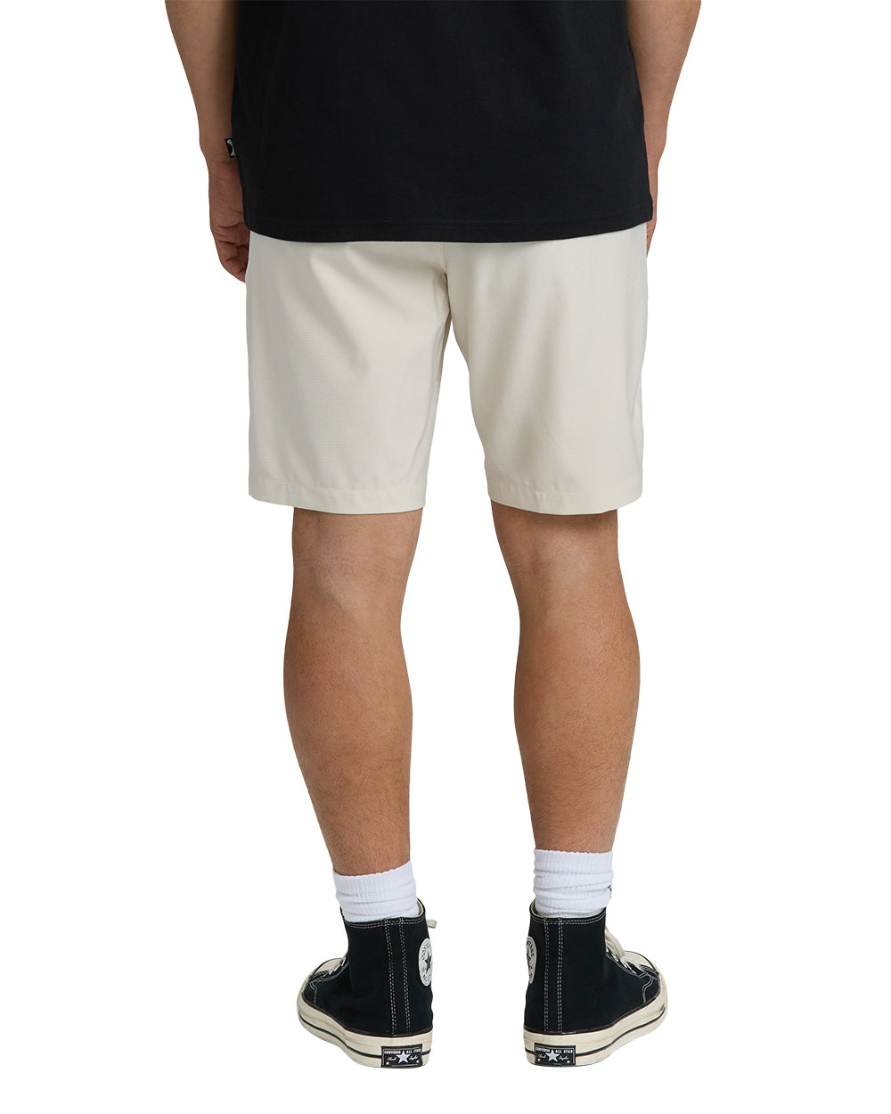 Oatmeal-colored hybrid shorts with 19-inch inseam, shown from back on model wearing black shirt and black sneakers.