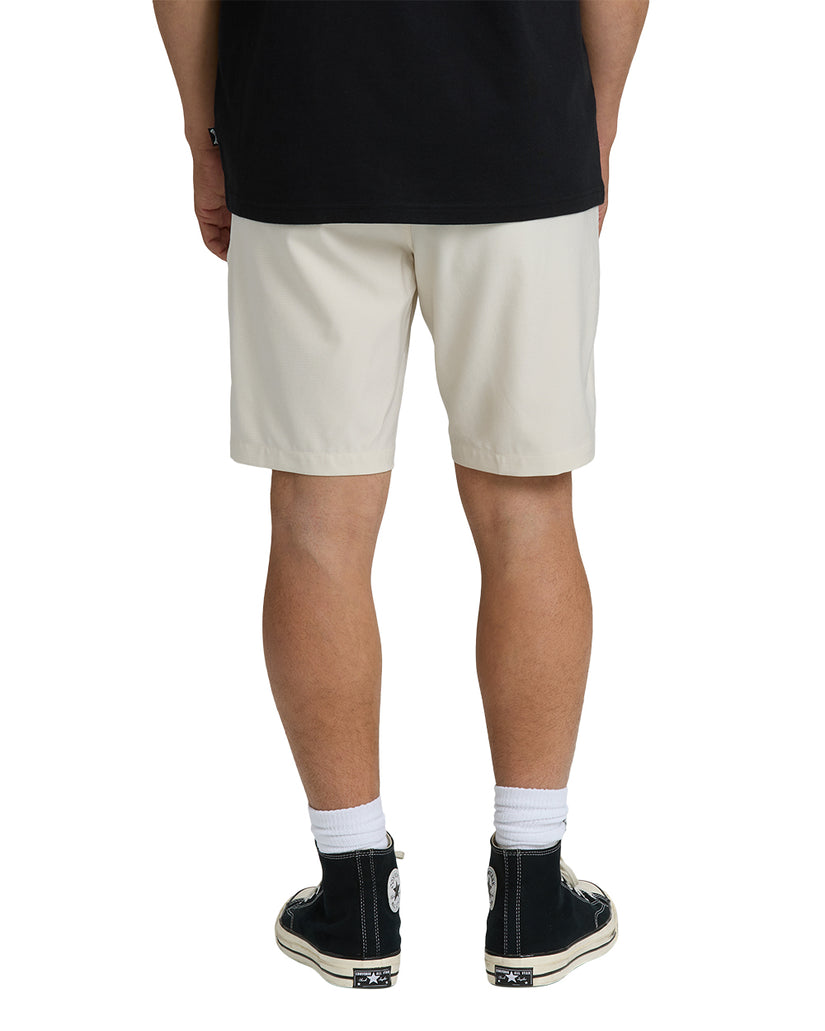 Oatmeal-colored hybrid shorts with 19-inch inseam, shown from back on model wearing black shirt and black sneakers.
