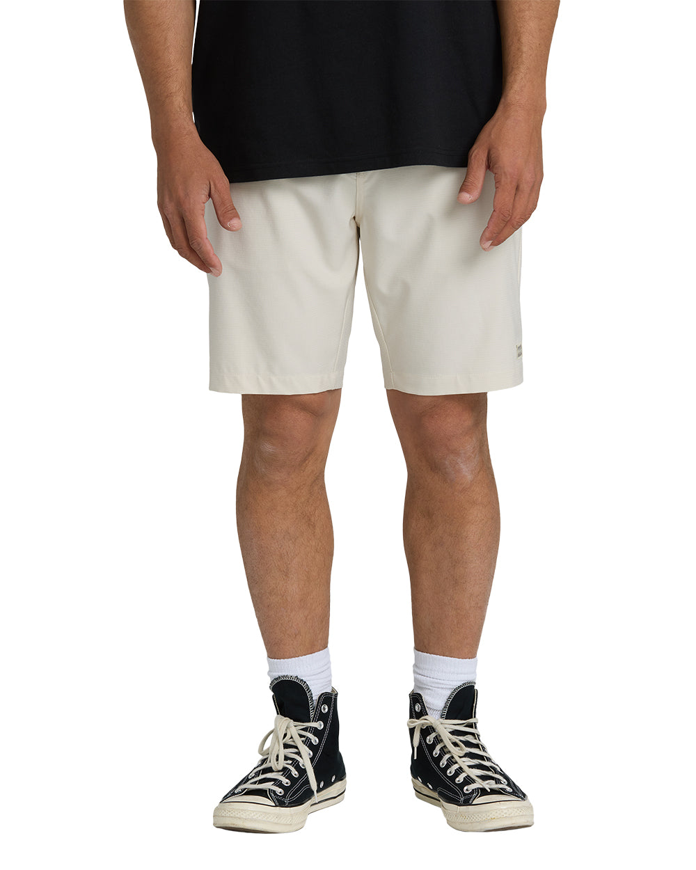 Oatmeal-colored hybrid shorts with a 19-inch inseam, displayed on a model wearing a black shirt and black sneakers.