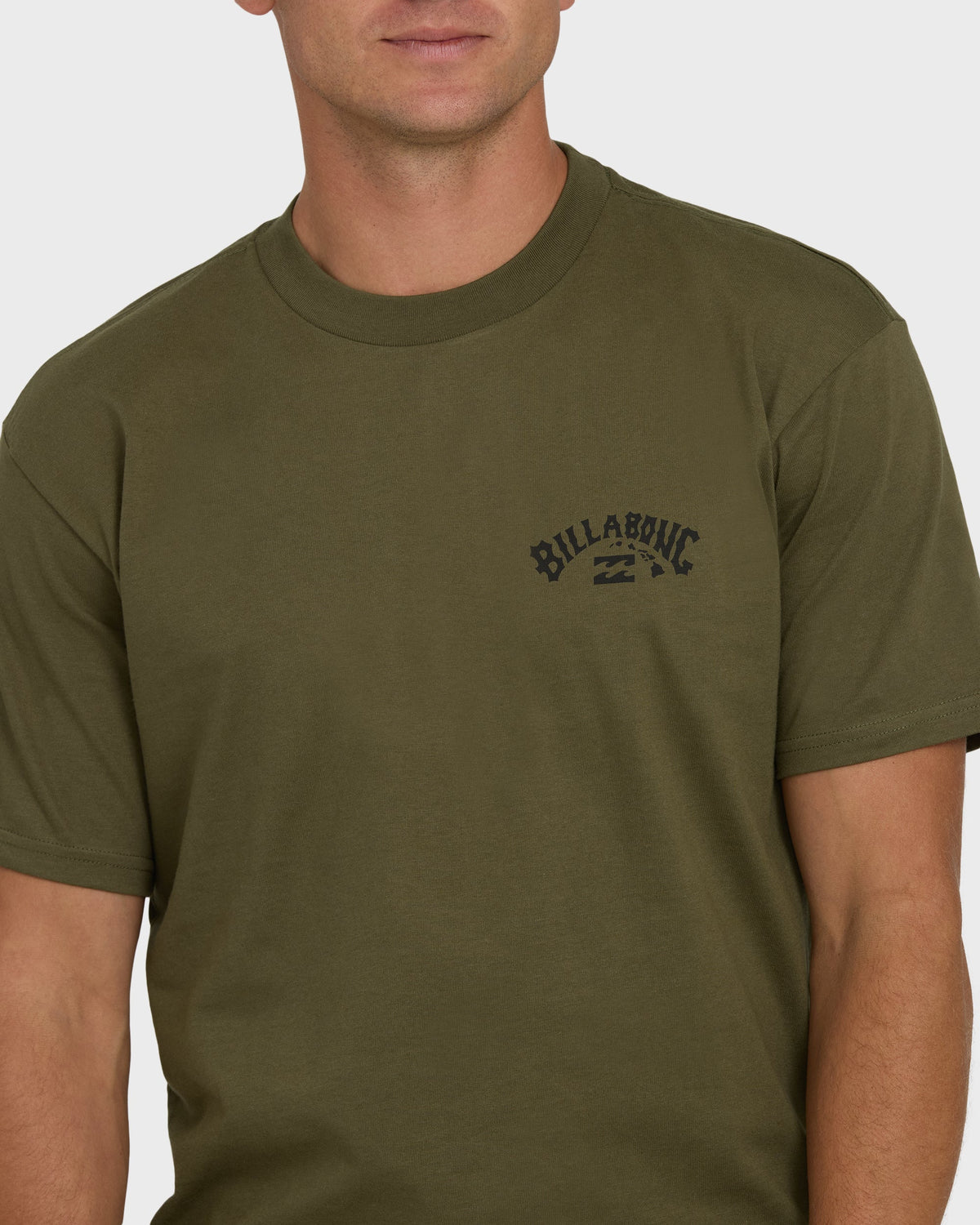 Man wearing military green short-sleeve t-shirt with Billabong logo on chest.