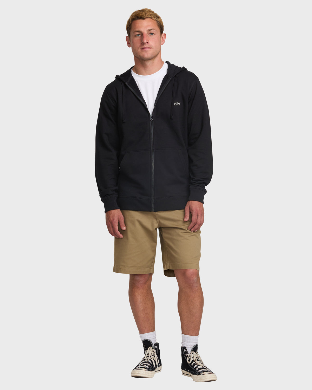 Black zip-up hooded sweatshirt with small logo on chest, styled with tan shorts.