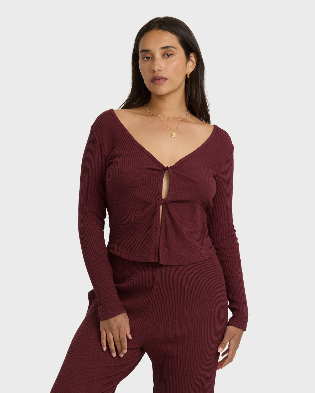Burgundy ribbed long sleeve knit top with V-neckline and front twist detail.