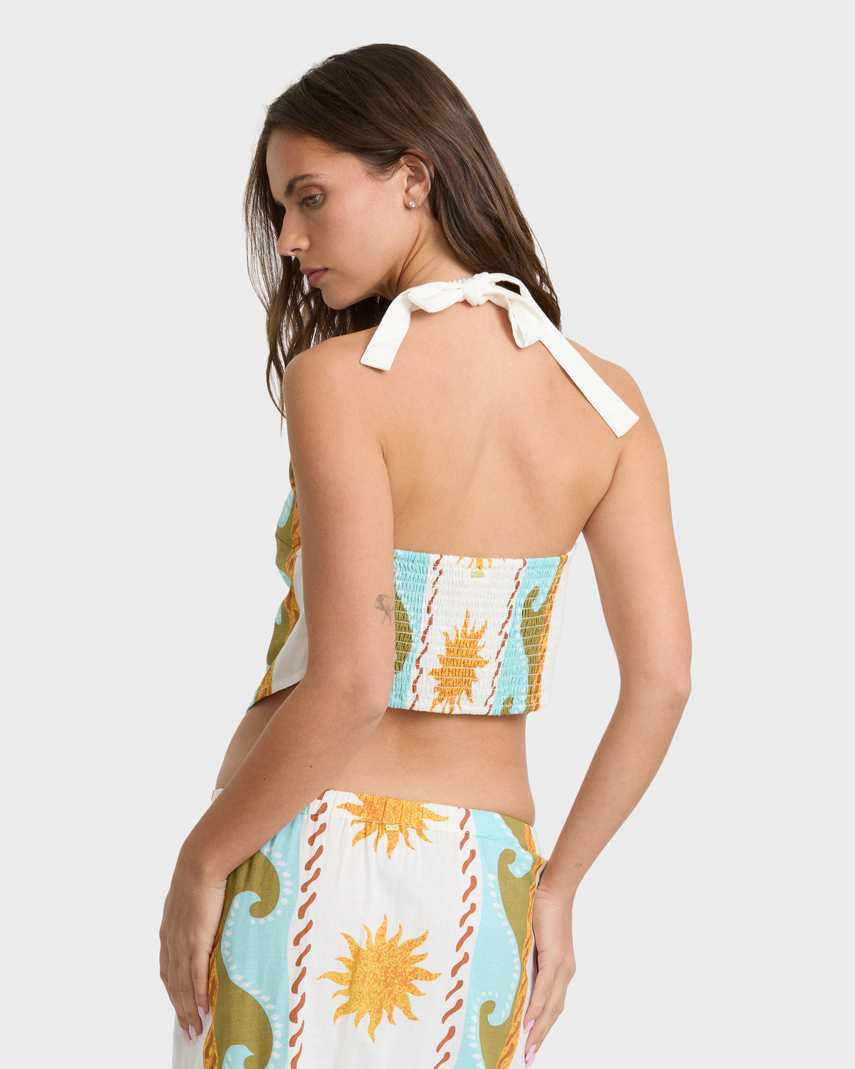 Woven halter top in cream with blue, gold, and orange sun and wave print, featuring tie closure at back.