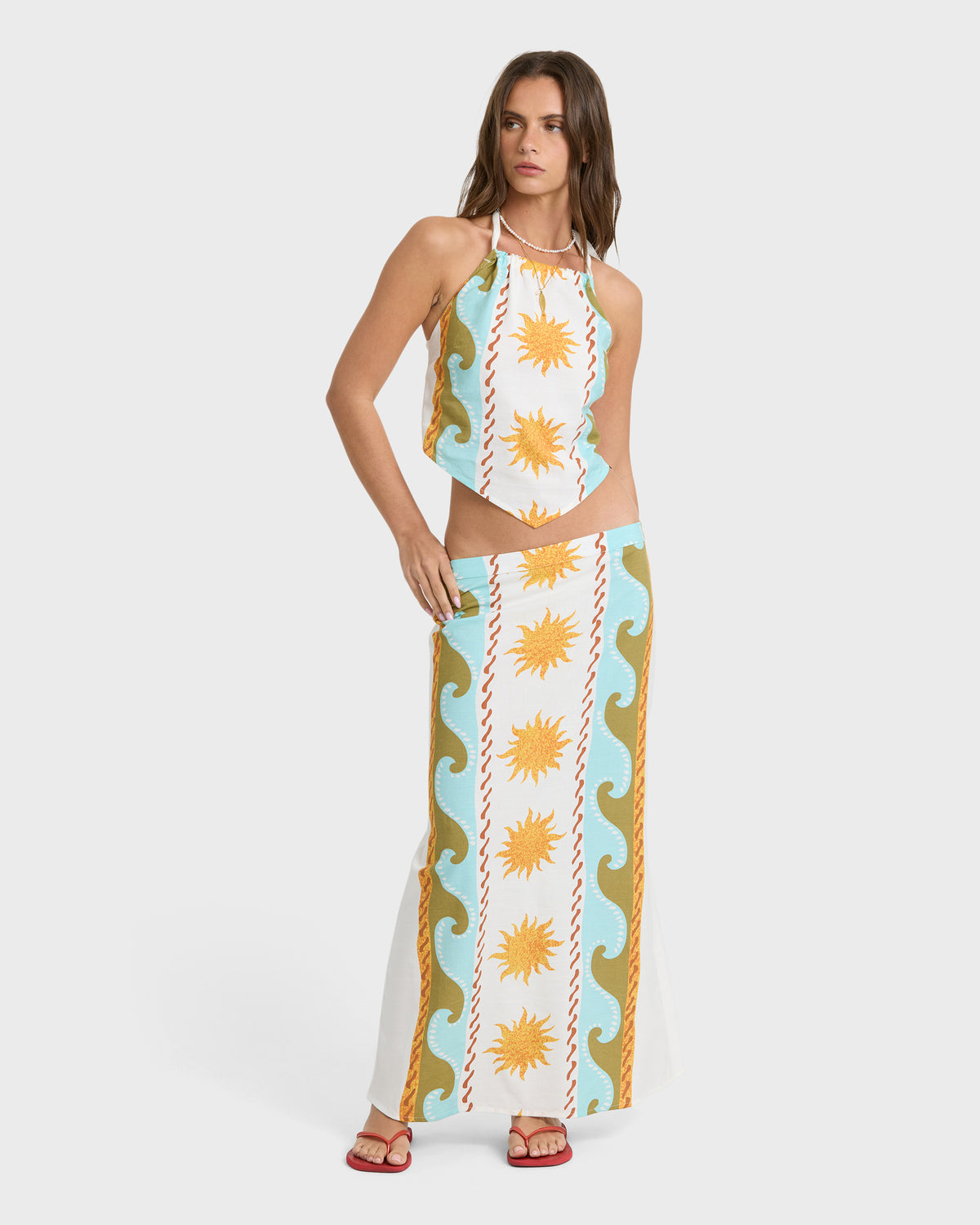 Woven halter top with sun and wave print in cream, blue, and gold tones paired with matching maxi skirt.