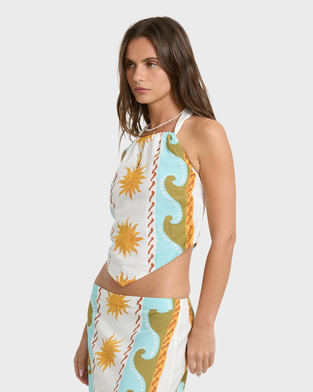 Cream halter top with sun and wave print in gold, blue, and red stripes.