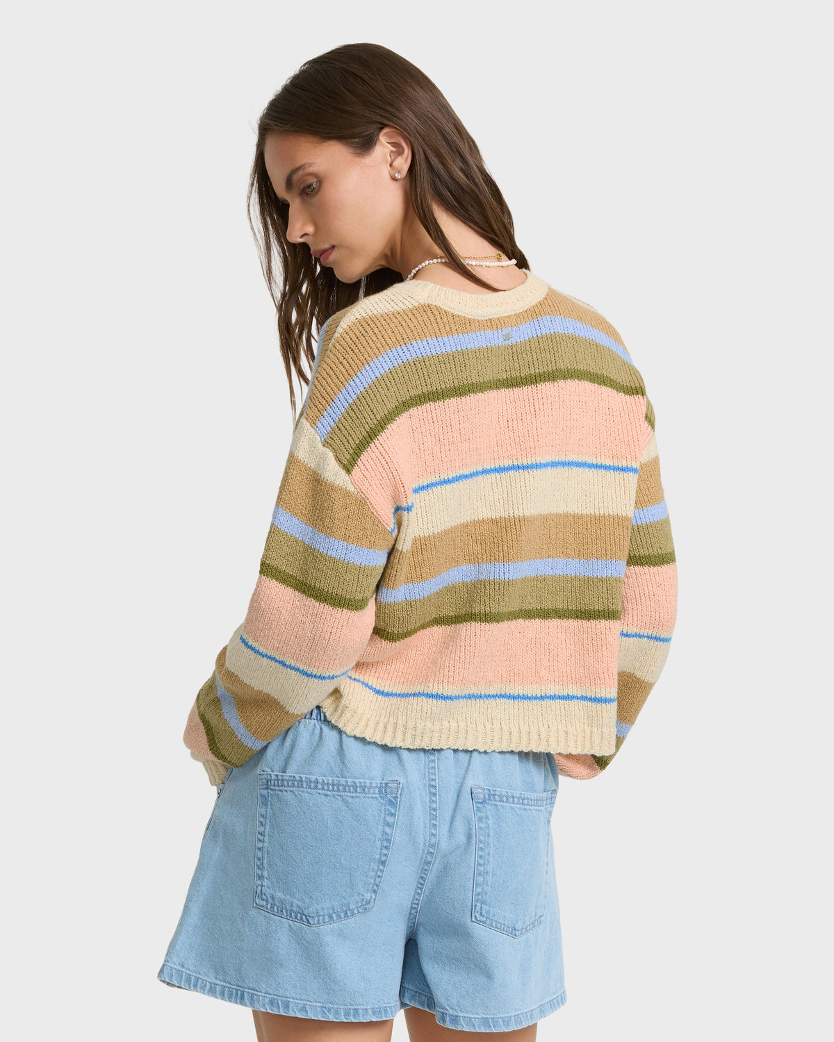 Light peach, tan, and olive striped knit sweater with blue accents worn with light blue denim shorts.