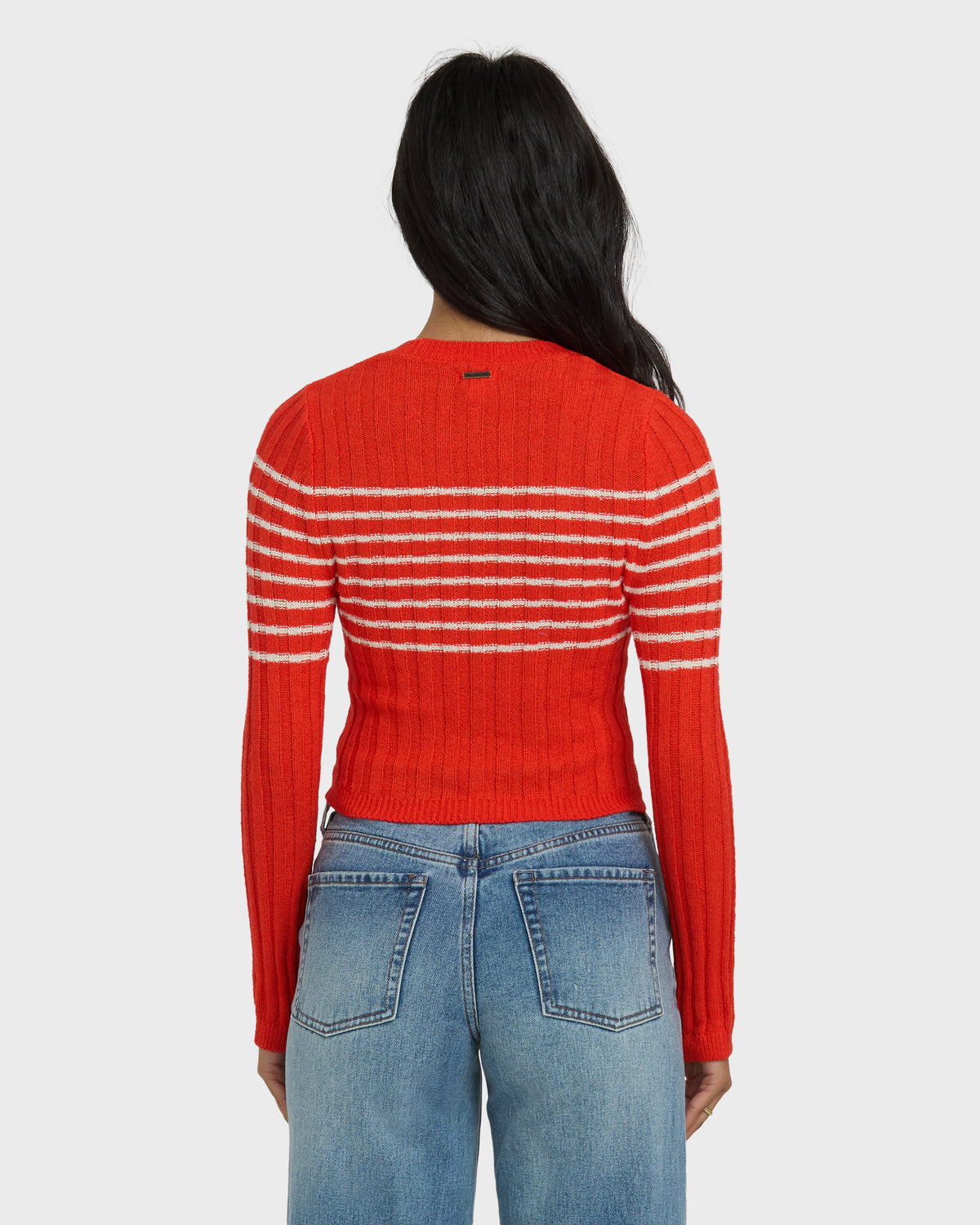 Red ribbed sweater with white horizontal stripes across the chest and sleeves, worn with blue jeans.