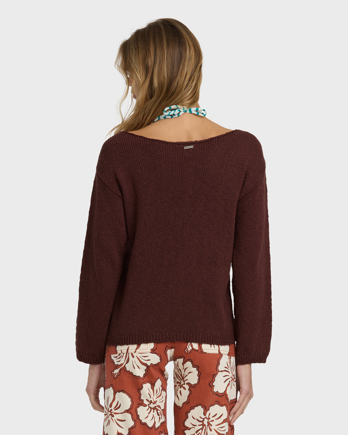 Brown ribbed knit sweater with wide neckline worn over floral patterned pants, shown from back view.