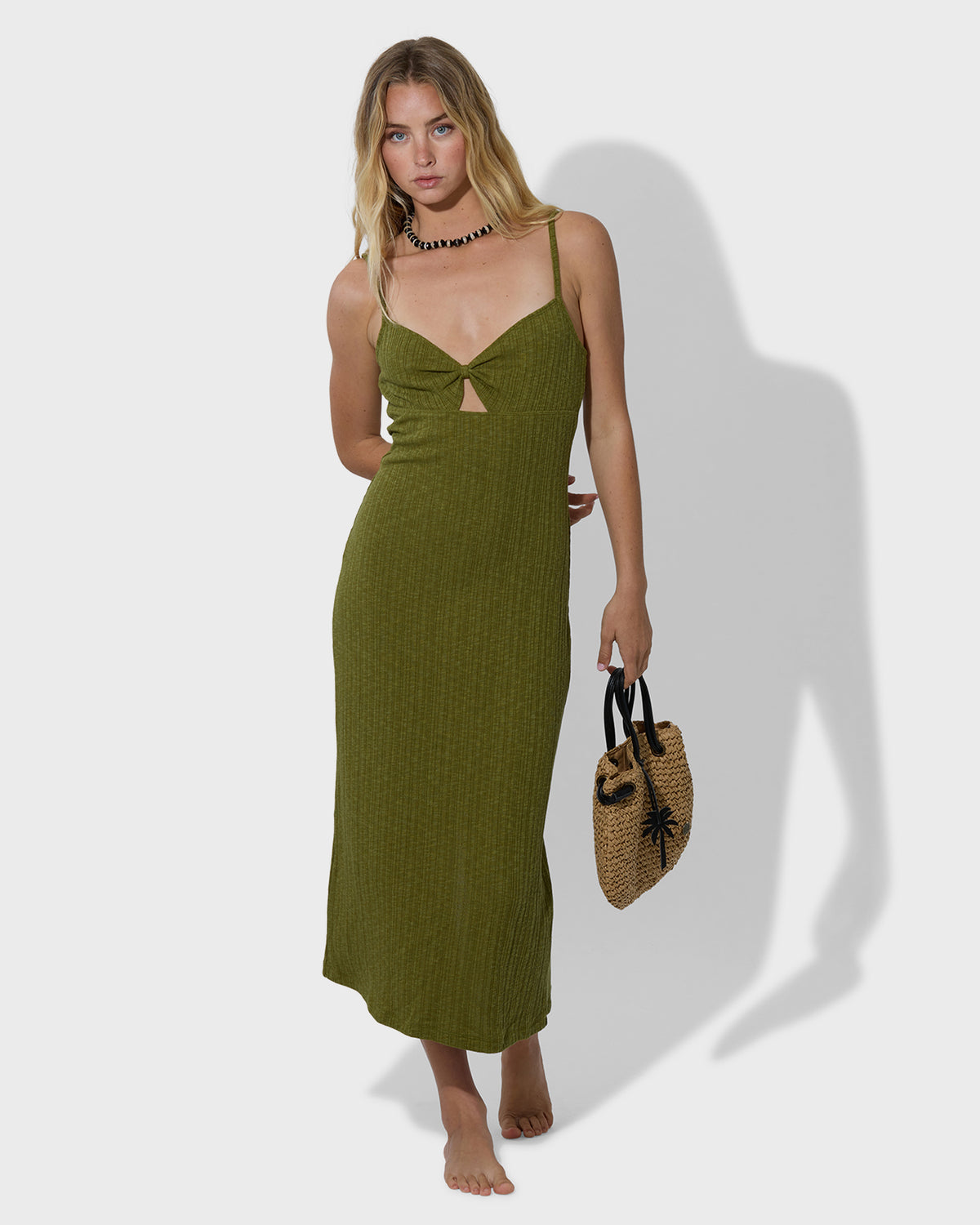 Tan woven straw mini crossbody tote with black handles, shown on model.