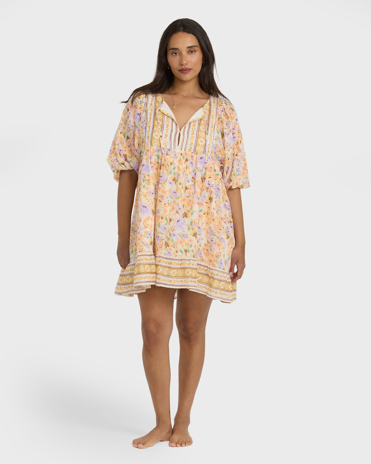 White mini dress with multicolored floral and geometric pattern, short puffed sleeves, and V-neckline.