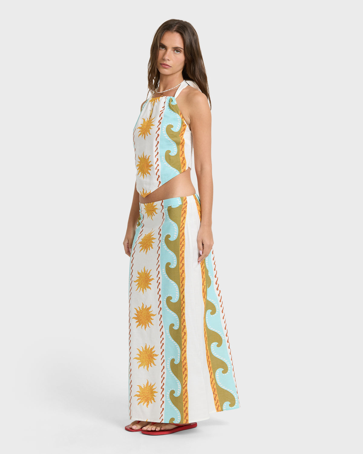 Midi skirt with sun and wave print in cream, blue, and gold tones, paired with matching crop top.