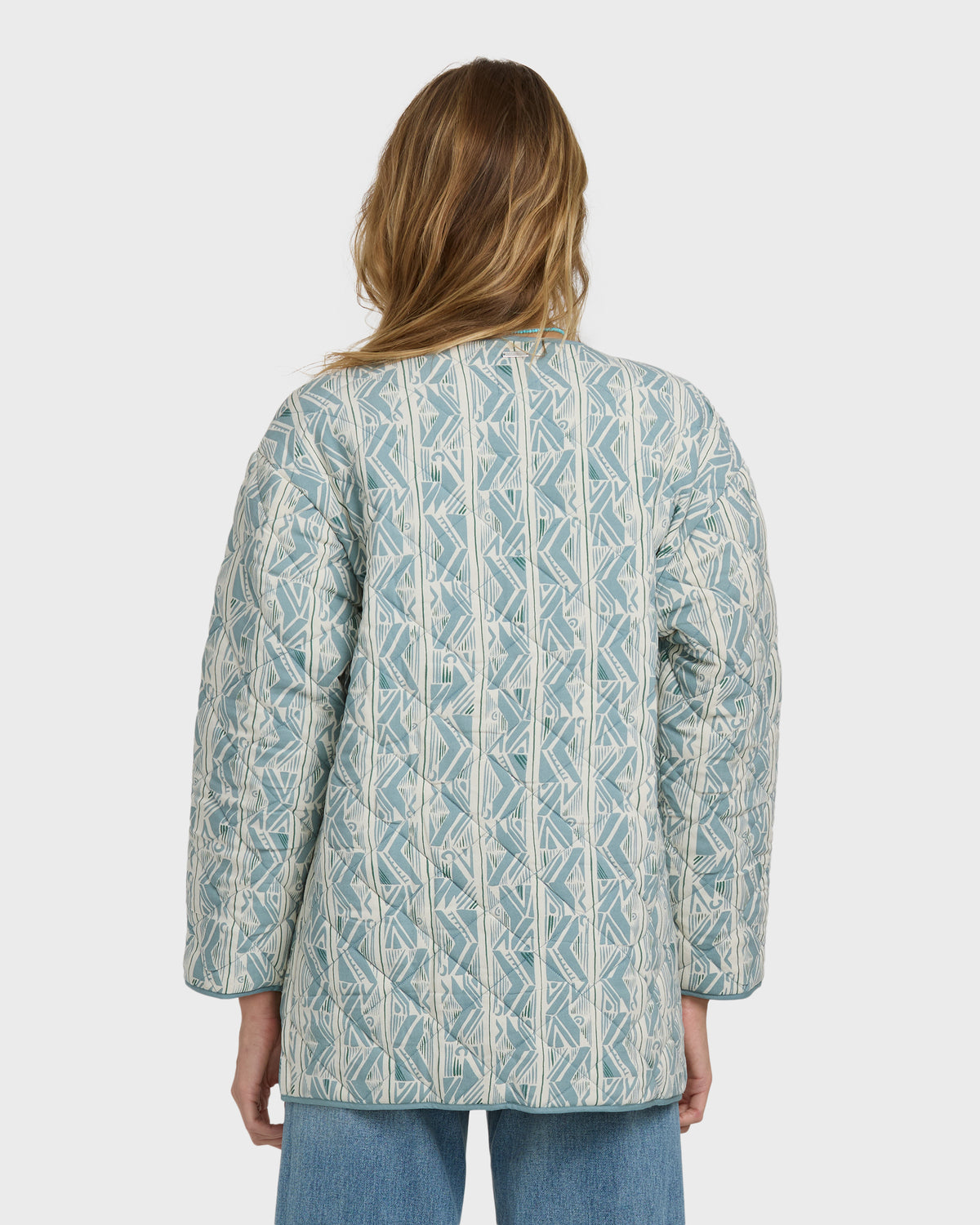 Mineral blue quilted jacket with geometric pattern worn over jeans, shown from back view.