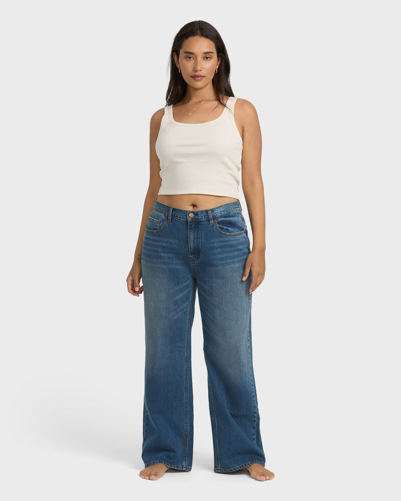 Faded blue denim straight leg pants with vintage wash worn with white tank top.