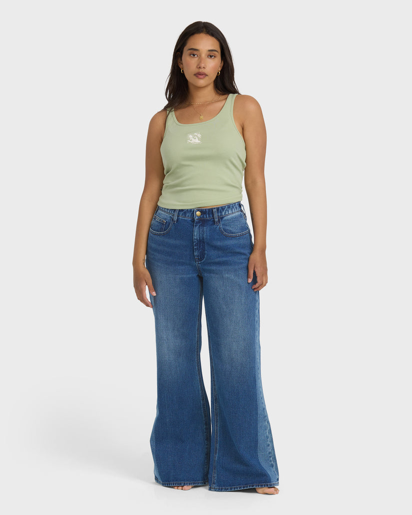 High-waist blue denim flare pants with distressed details, styled with a sage green tank top.