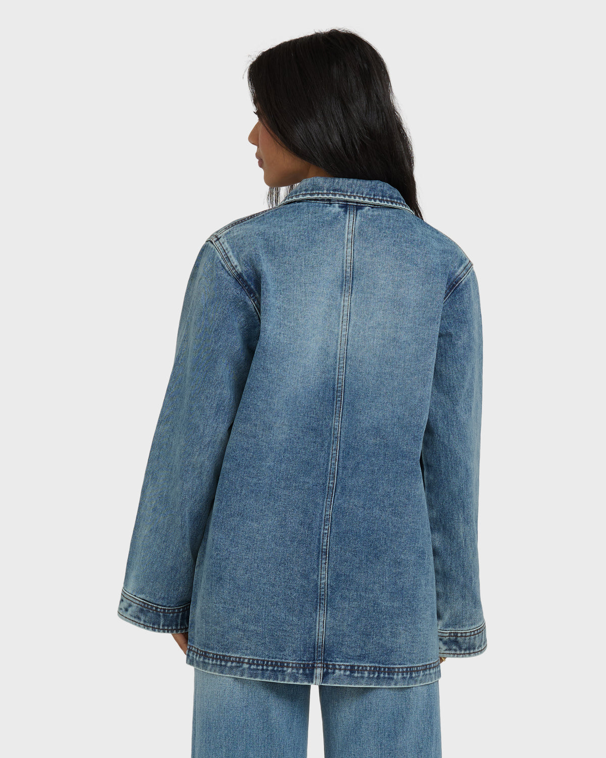 Medium-wash denim chore coat with collar and center seam, shown from back on model.