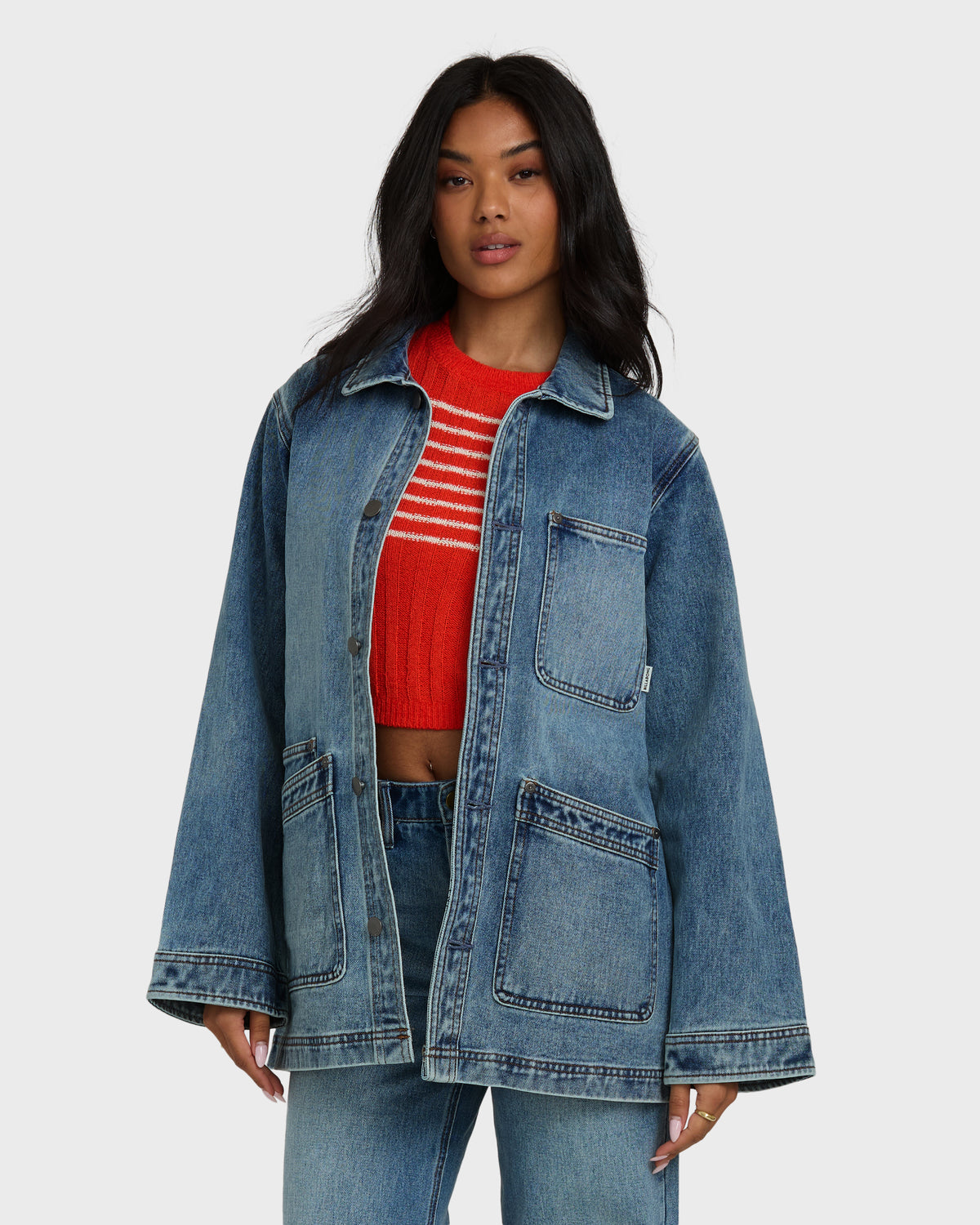 Medium-wash denim chore coat with collar, button front, and two large patch pockets.