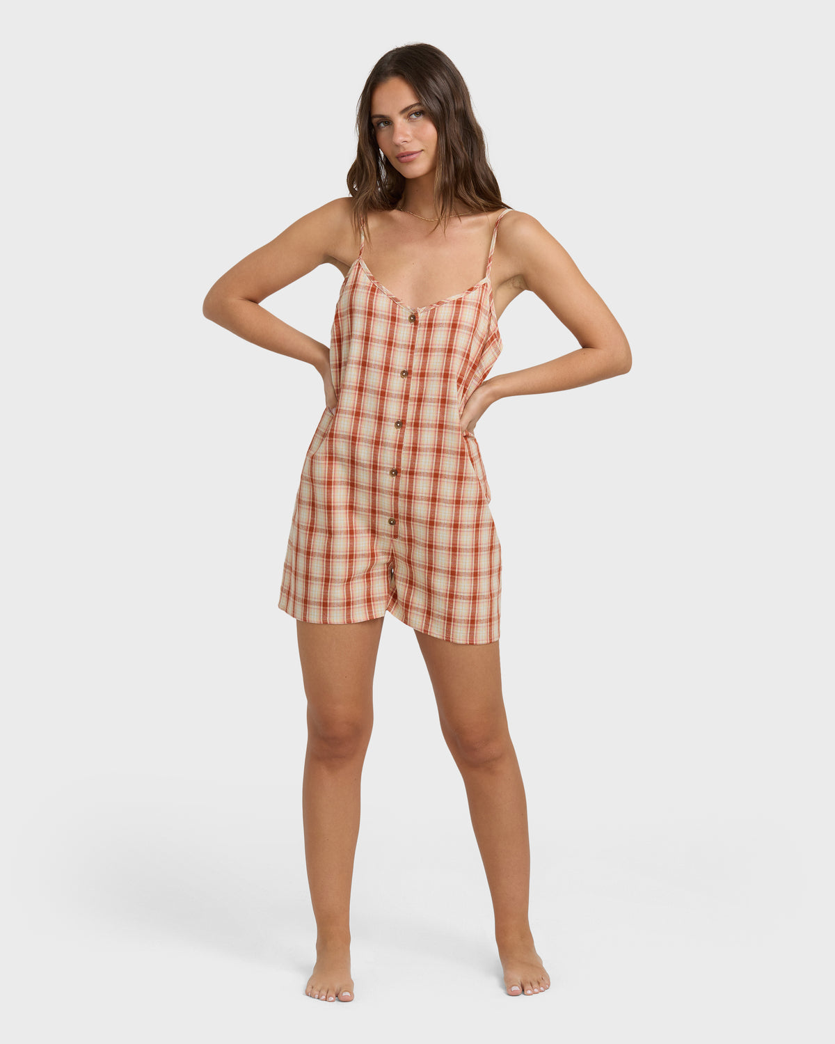 Red and white plaid romper with thin straps, button front, and short legs on model.