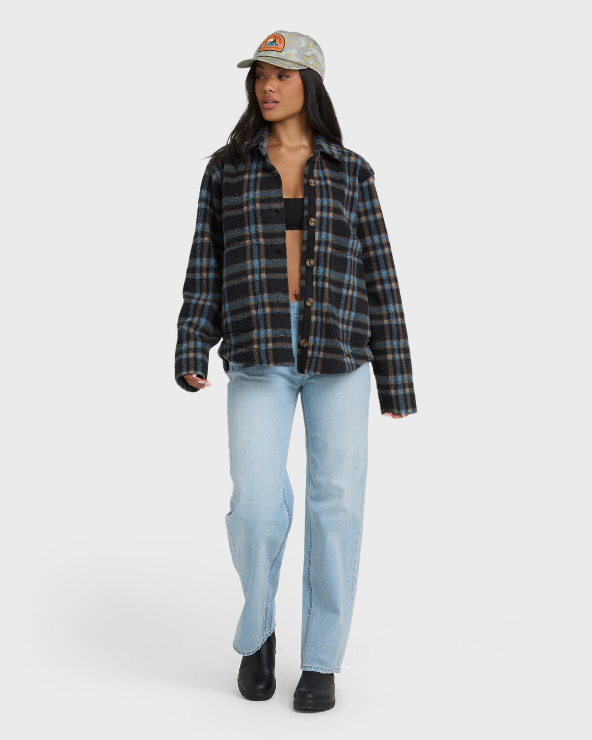 Black and blue plaid sherpa shacket with button front worn over black crop top and light blue jeans.