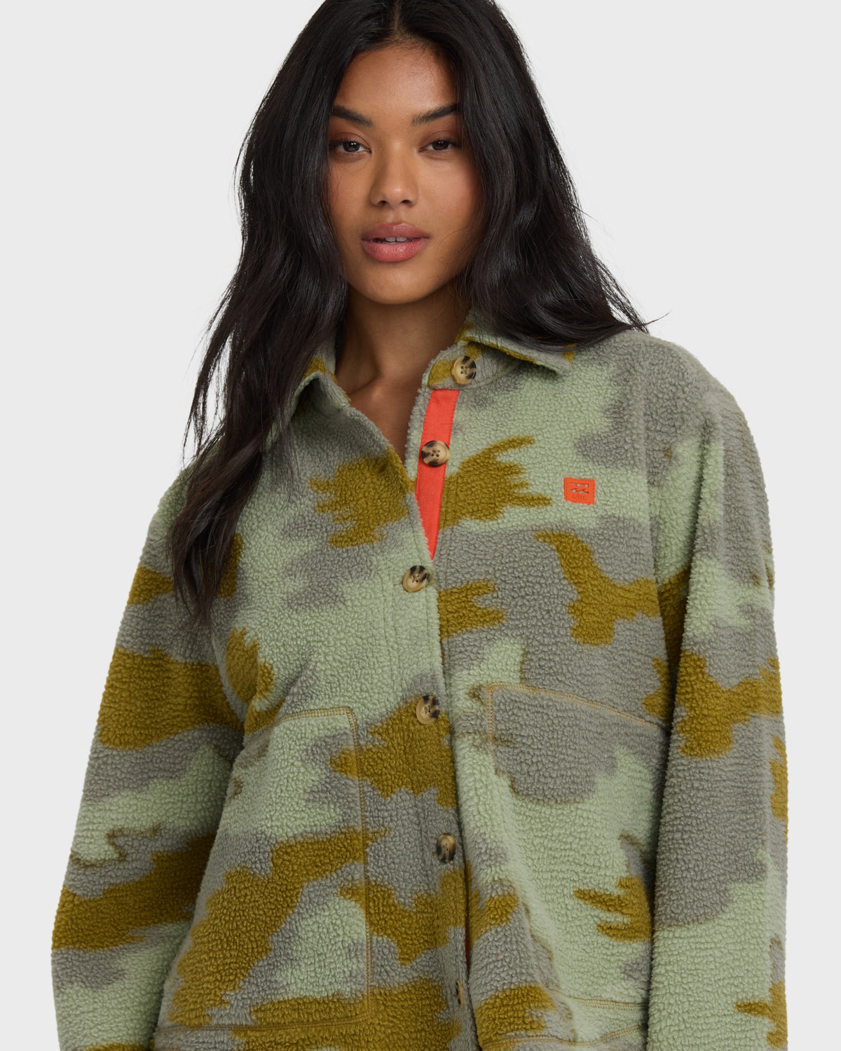 Camouflage patterned sherpa shacket in sage and mustard tones with button front and red interior placket.