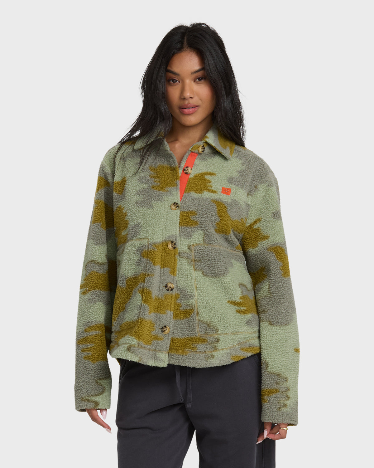 Camouflage sherpa shacket with olive and yellow pattern, button front, and red interior visible at collar.