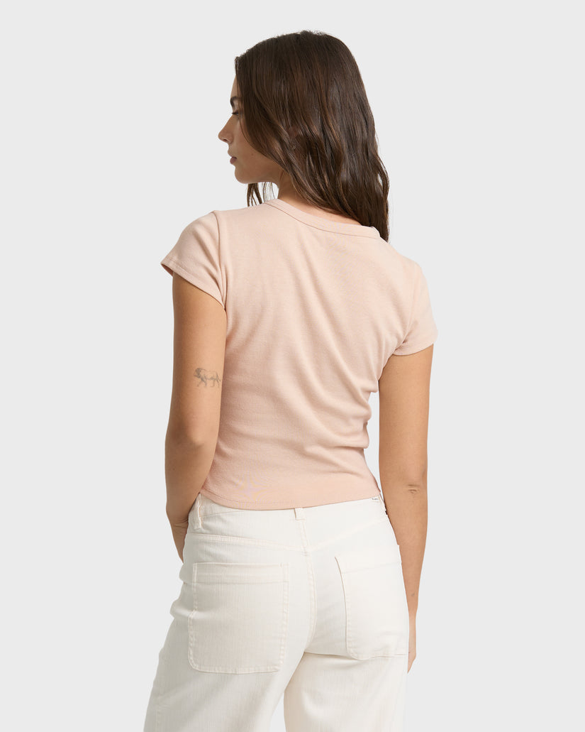 Oatmeal short-sleeve t-shirt with rolled cuffs worn with cream-colored pants, shown from back view.