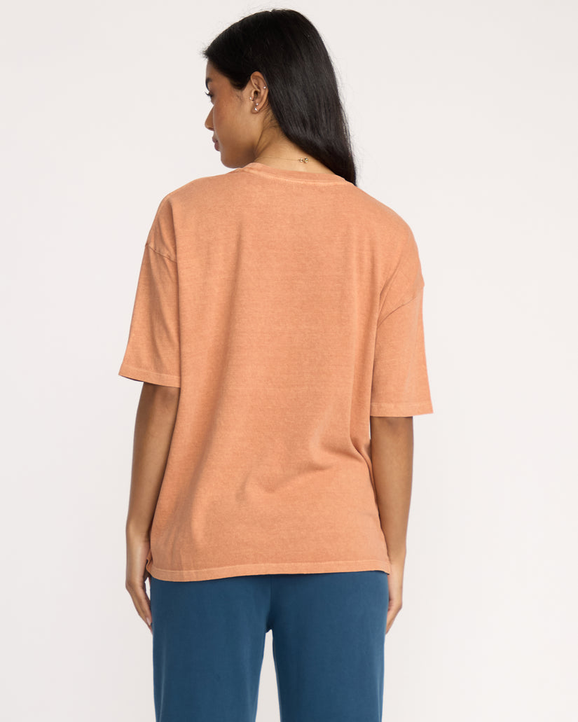Sunburnt-colored short sleeve tee on model shown from back view with dark blue pants.
